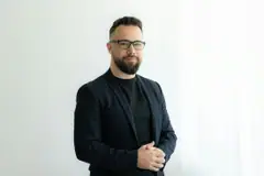 Retrato de Caio Resende, de óculos, barba e blazer escuro